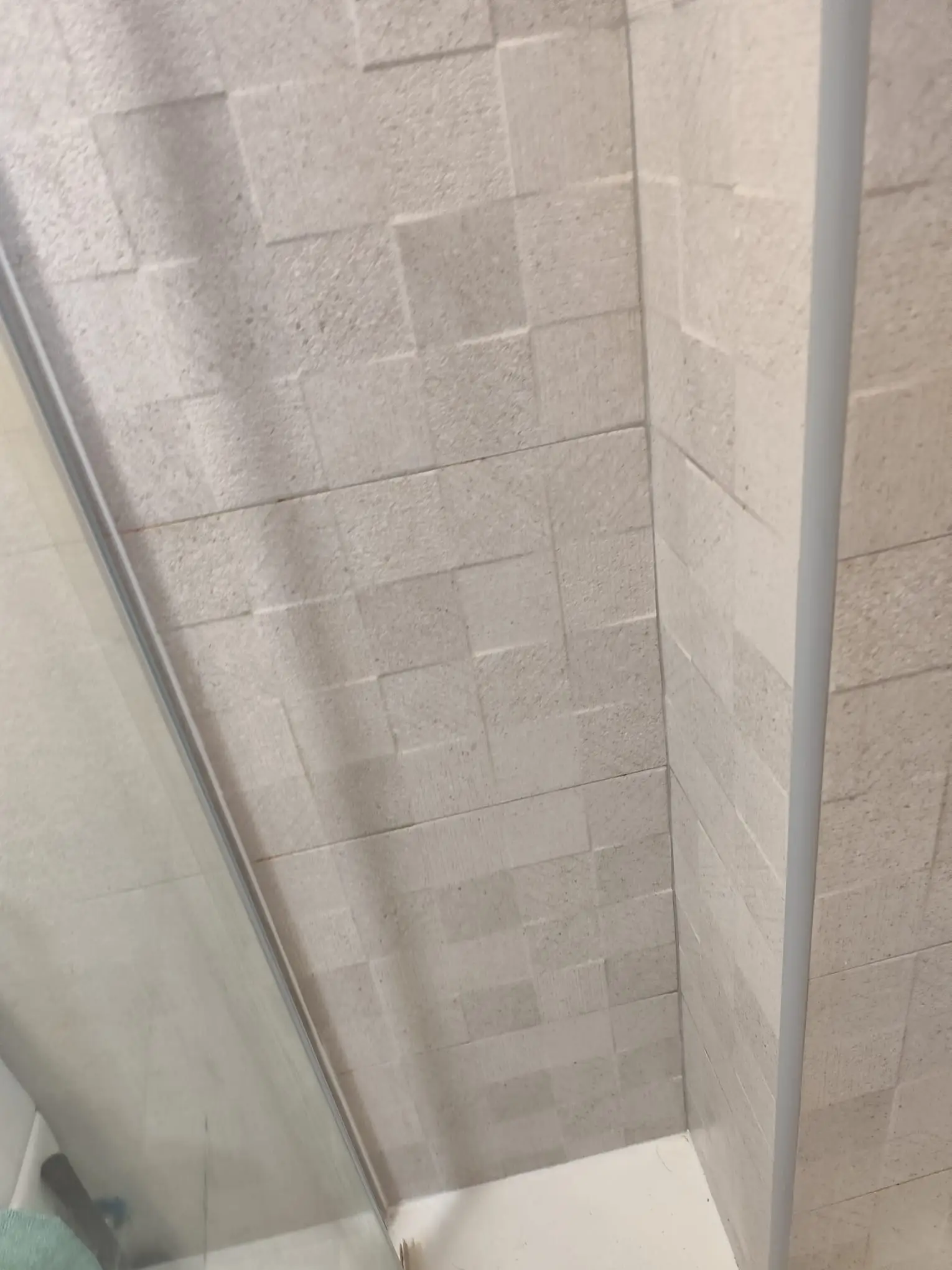 Reforma de baño con revestimiento de azulejos texturizados en tonos crema y mampara en Etxebarri