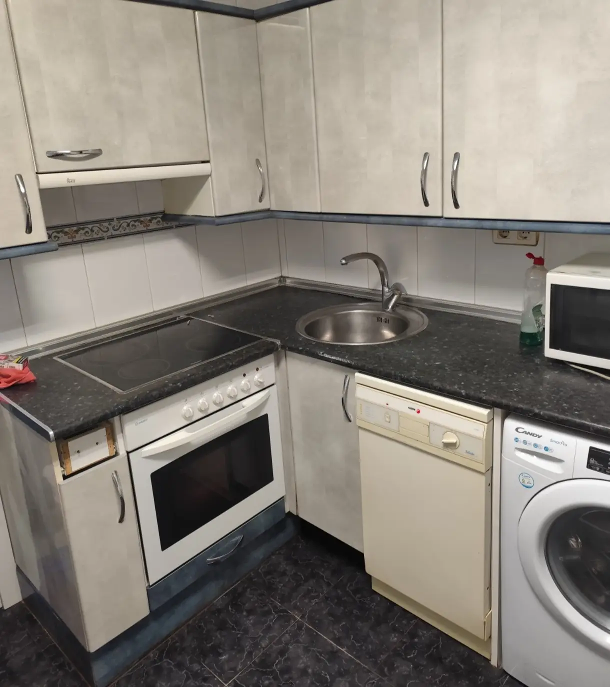Reforma de cocina con encimera oscura, fregadero circular y mobiliario en tonos grises en Etxebarri