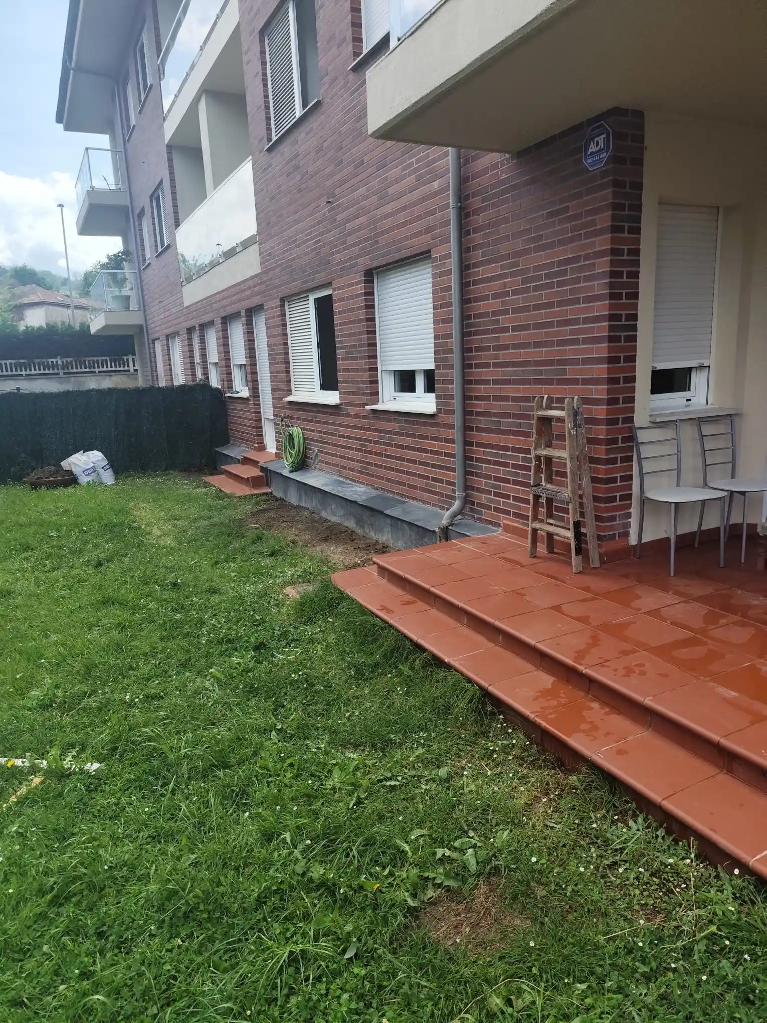 Rehabilitación de fachada de ladrillo visto con porche de gres cerámico y jardín en Etxebarri